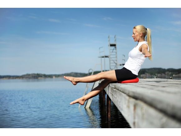 Femme assise sur le coussin coccyx SITFIT® Rond 36 cm au bord de l'eau Femme assise sur le coussin coccyx SITFIT® Rond 36 cm au bord de l'eau