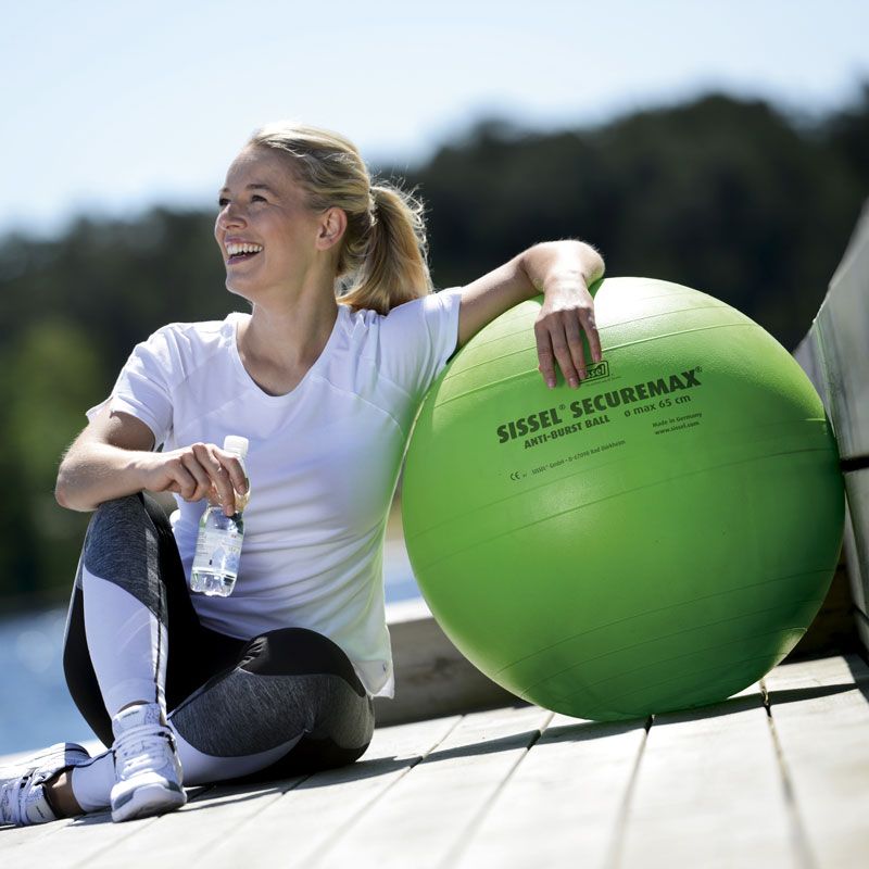 Femme accoudée sur le ballon de gym SISSEL® SECUREMAX® Ø65 cm vert Femme accoudée sur le ballon de gym SISSEL® SECUREMAX® Ø65 cm vert
