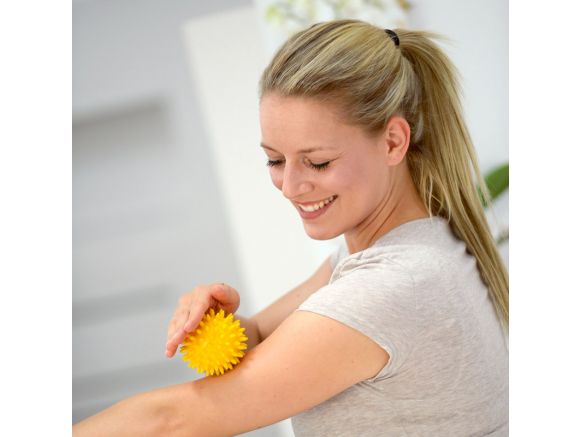 Femme pratiquant l'auto-massage avec une balles hérisson SISSEL® SPIKY BALL 8 cm jaune Femme pratiquant l'auto-massage avec une balles hérisson SISSEL® SPIKY BALL 8 cm jaune