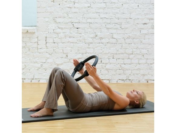 Femme allongée sur un tapis de gym avec un Pilates Circle 36 cm Femme allongée sur un tapis de gym avec un Pilates Circle 36 cm