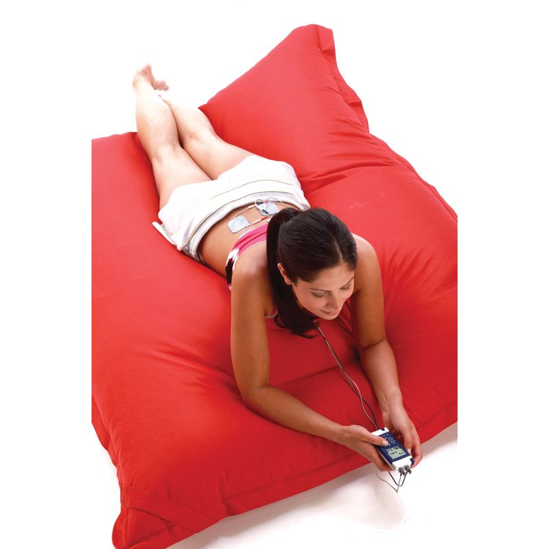 Femme allongée dans un coussin avec le stimulateur neuromusculaire CefarCompex REHAB X2 + chargeur 4 piles