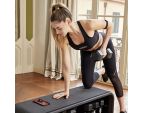 Jeune femme utilsant le banc de musculation multifonction Technogym Bench avec haltère
