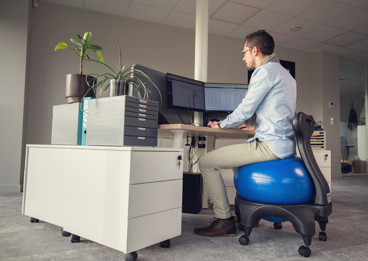 Stéphane assis sur une Tonic Chair® Originale bleu au bureau