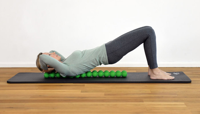 Exercice d'une femme au sol avec le SPINEFITTER et le tapis de gym Pro SISSEL®