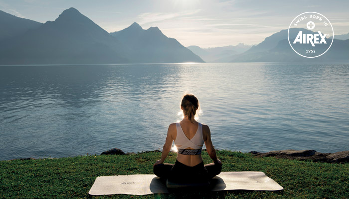 Femme regardant la mer et les montagnes sur un tapis de yoga AIREX®
